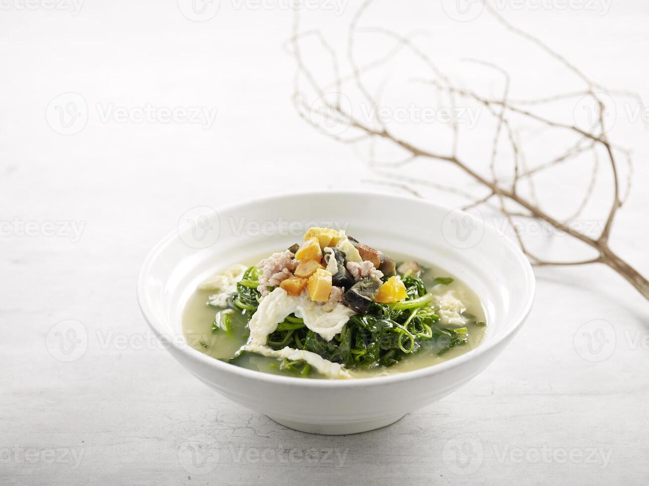 Poached Chinese Spinach with Egg Trio in Superior Stock served in a bowl isolated on wooden board side view on grey background photo
