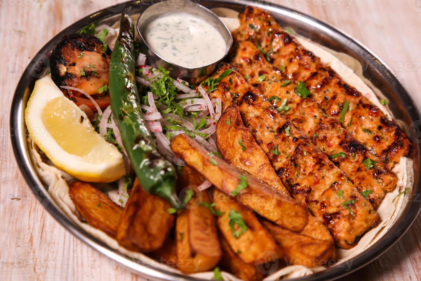 Chicken Kabab Dajaj with salad, wedges, lemon and dip served in dish isolated on background top view of arabic food photo