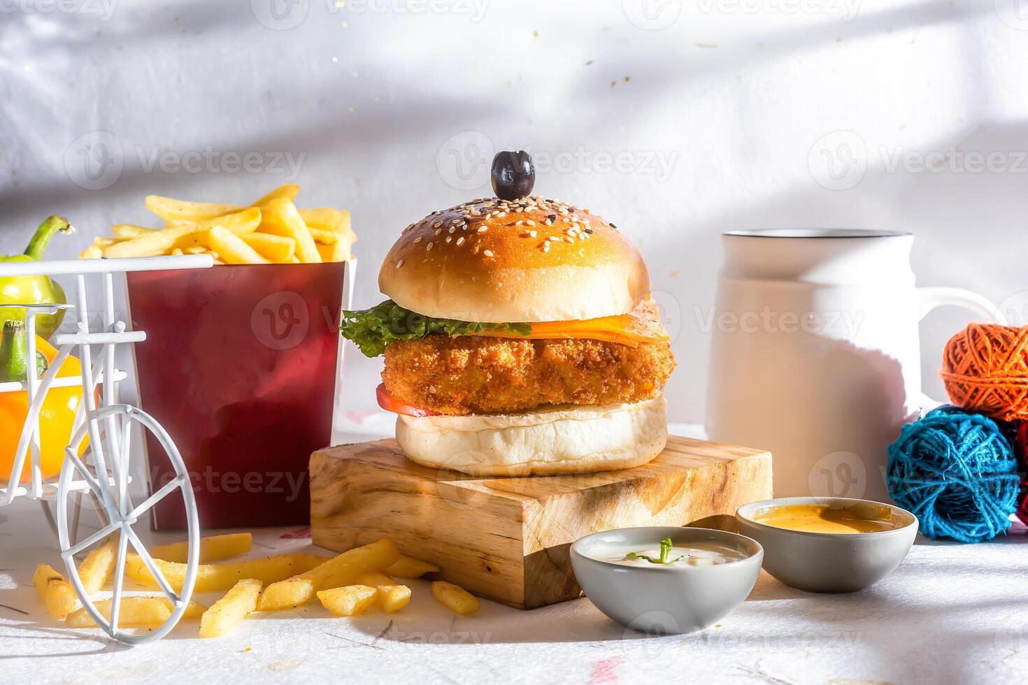 Fish Burger with fries tomato, and green chilli isolated on wooden board side view of american fast food photo