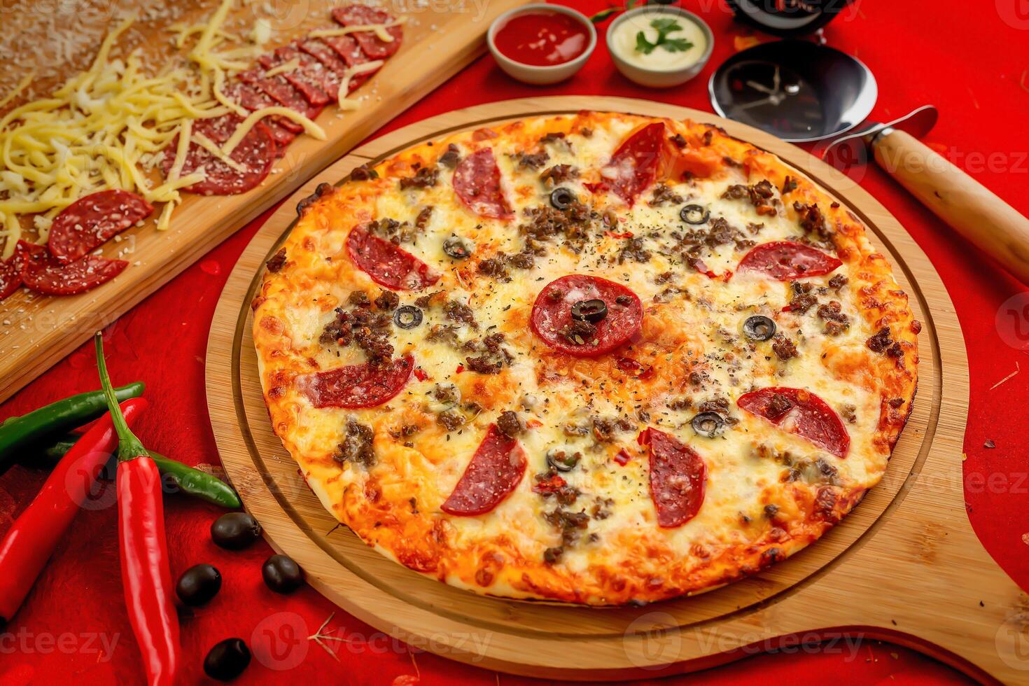 Beef Pepperoni pizza with tomato sauce and mayo isolated on wooden board top view of italian food on wooden background photo