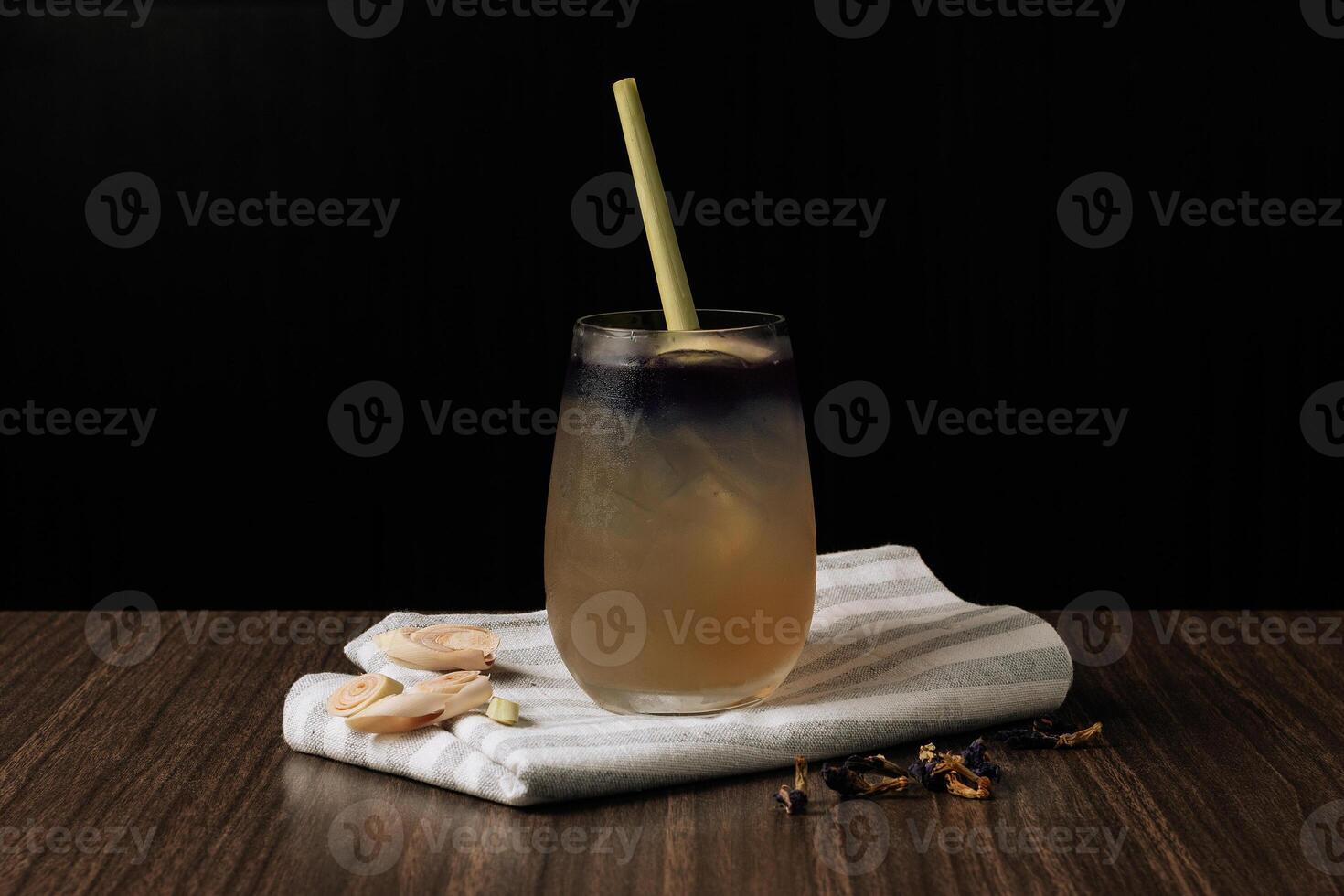 Iced Thai Lemongrass And Butterfly Pea with straw isolated on wooden table side view photo