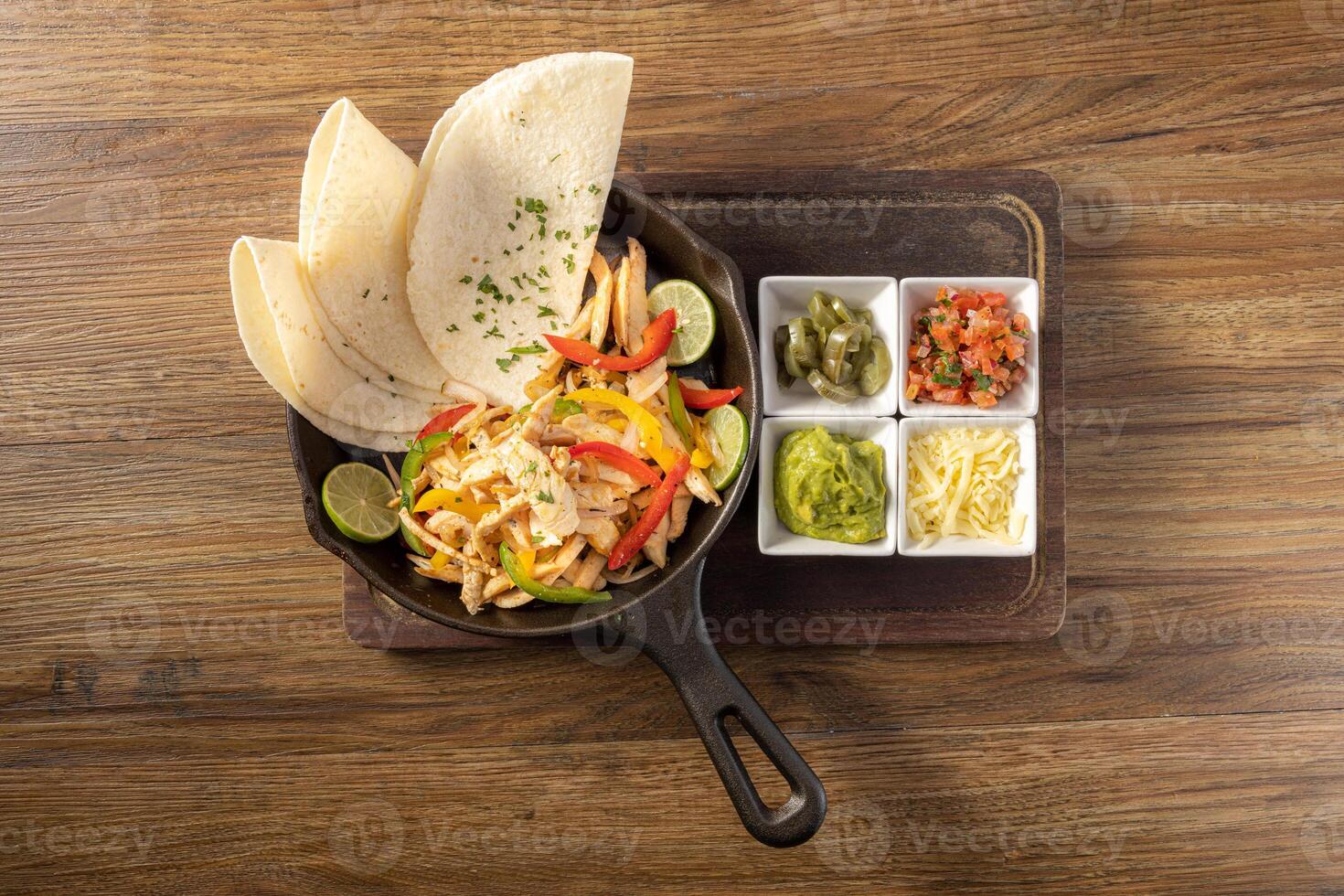 Mexican chicken fajita with bell peppers, grilled vegetables and onions top view on dark wooden background photo