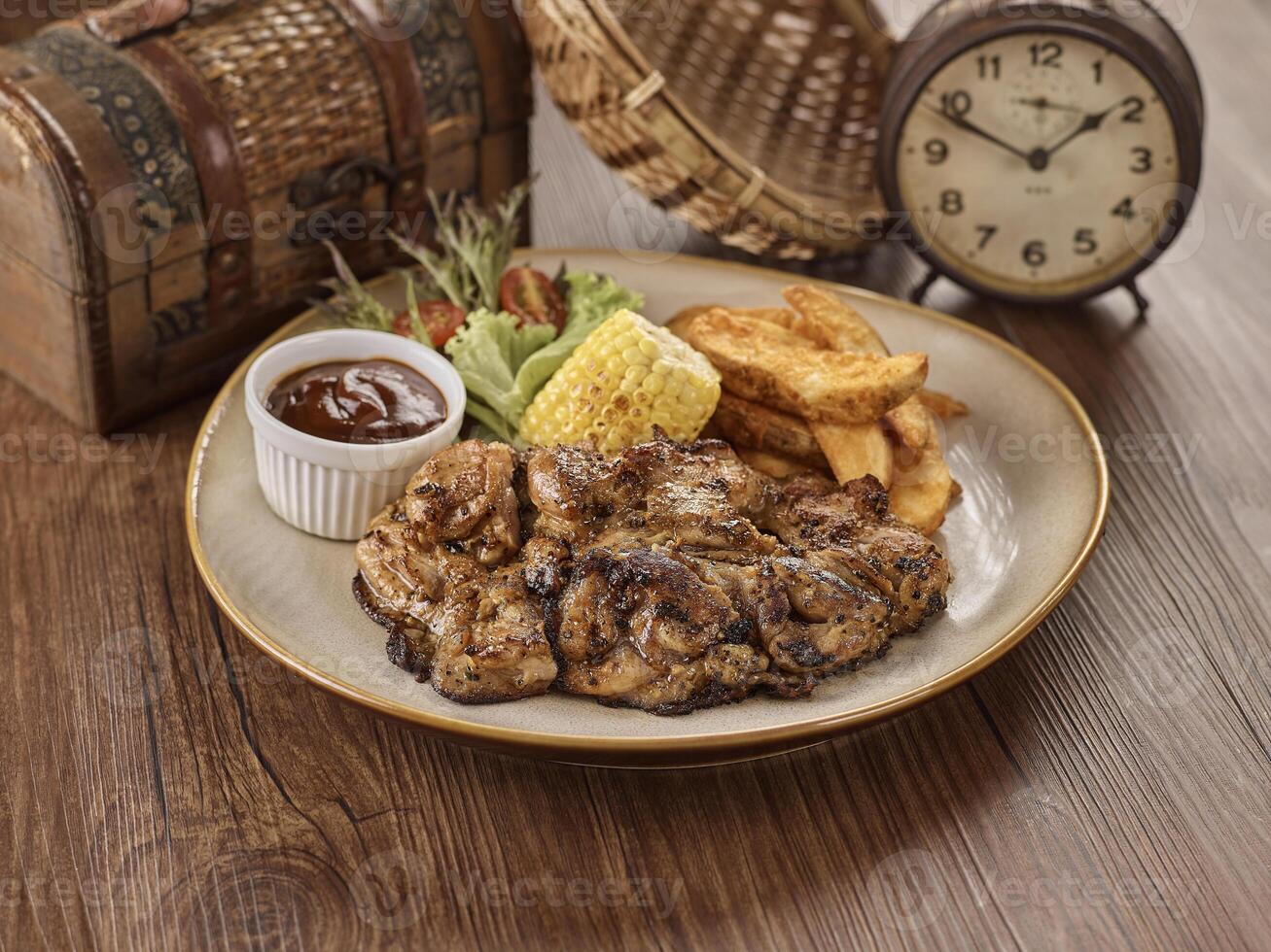 Grilled Chicken Chop, chips and corn in a dish isolated on dark wooden table side view singapore food photo