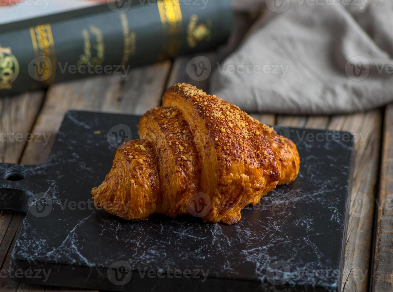 cheese croissant served in a dish isolated on cutting board side view of breakfast on wooden background photo