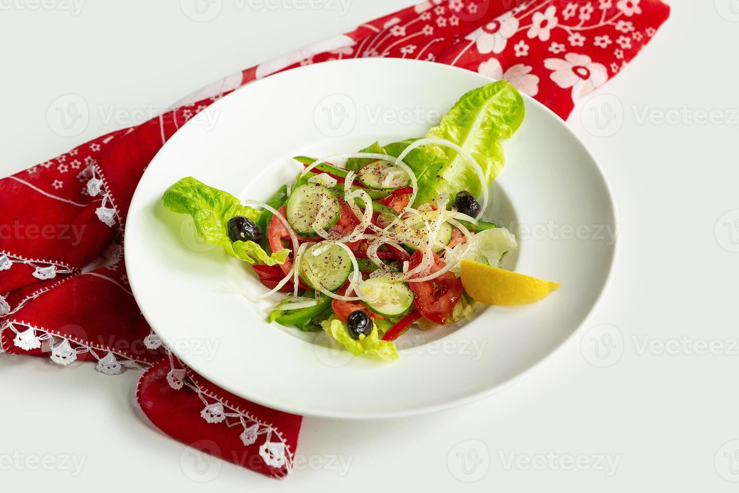 Fresh Healthy green salad in a dish isolated on colorful table cloth top view on grey background tomato, cucumber, onion, spinach, lettuce and sesame photo