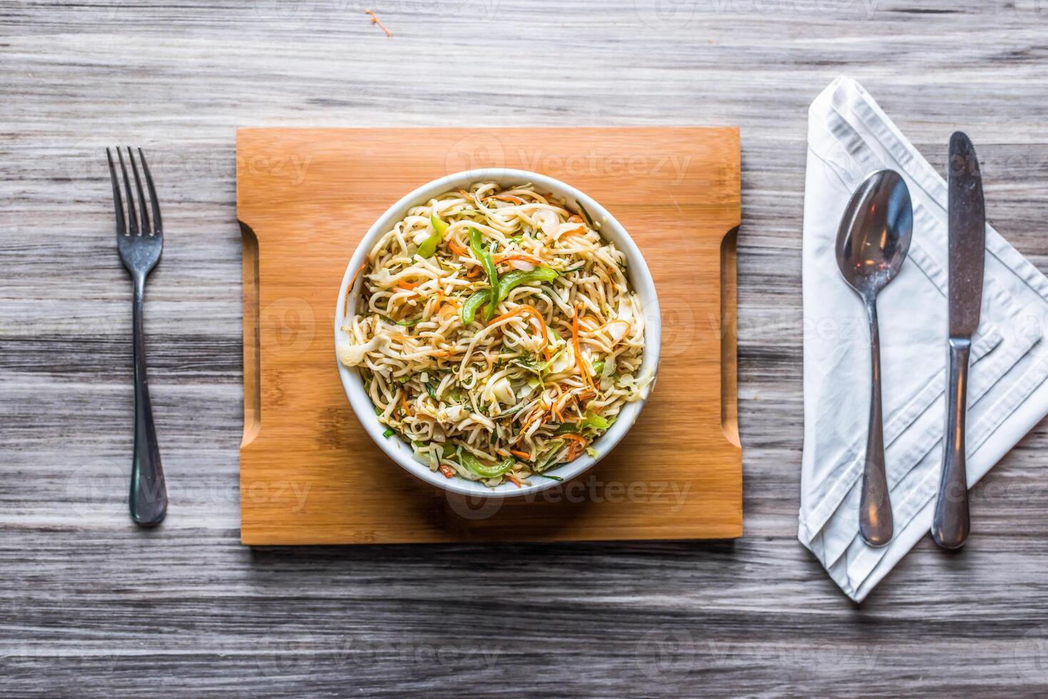 hakka tallarines vegetales con cuchara y pañuelo de papel aislado en de madera tablero parte superior ver en mesa comida rápida foto