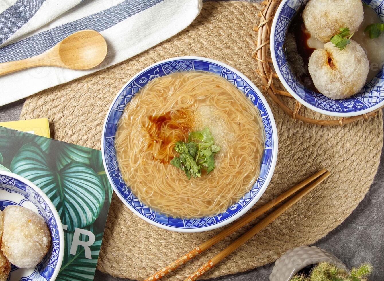 clear noodles with chopsticks and spoon served in bowl isolated on table top view of chinese food photo