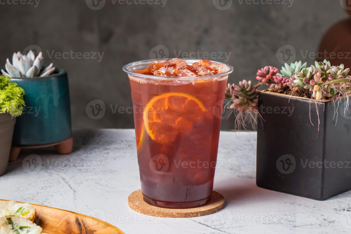 Thai lemon tea served in disposable glass with lime slice isolated on wooden board side view of taiwanese ice drink photo