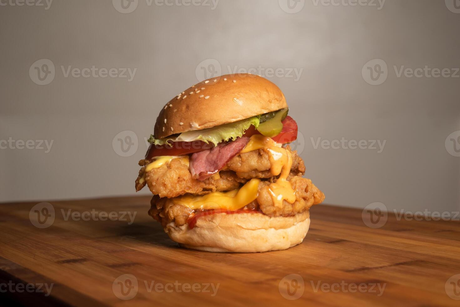 Supreme Crispy Chicken Cheese Burger with Bacon isolated on wooden table top view of french unhealthy junk fastfood photo