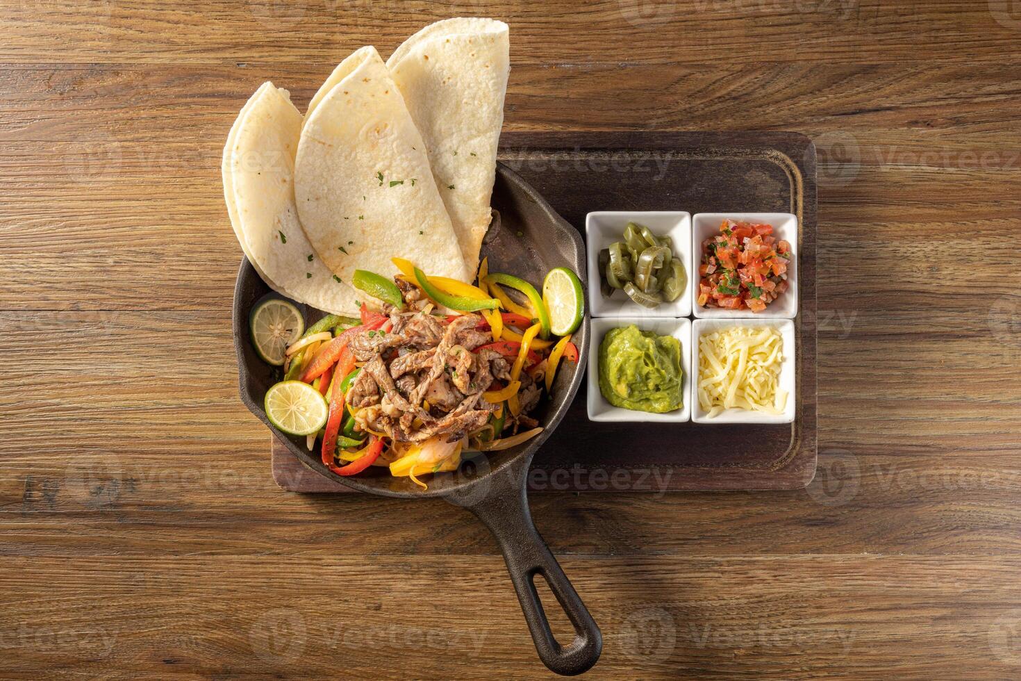 Mexican Beef fajita with bell peppers, grilled vegetables and onions top view on dark wooden background photo