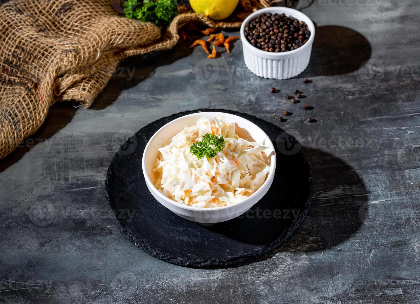 Freshly Made Coleslaw shredded white cabbage, mayonnaise and grated carrot in bowl side view on dark background photo