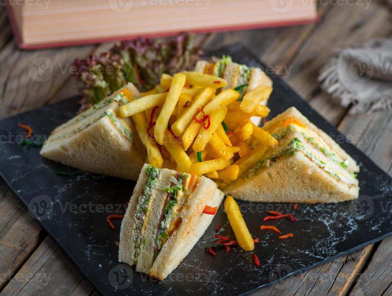 club sandwich with fries isolated on cutting board side view of fastfood on wooden background photo