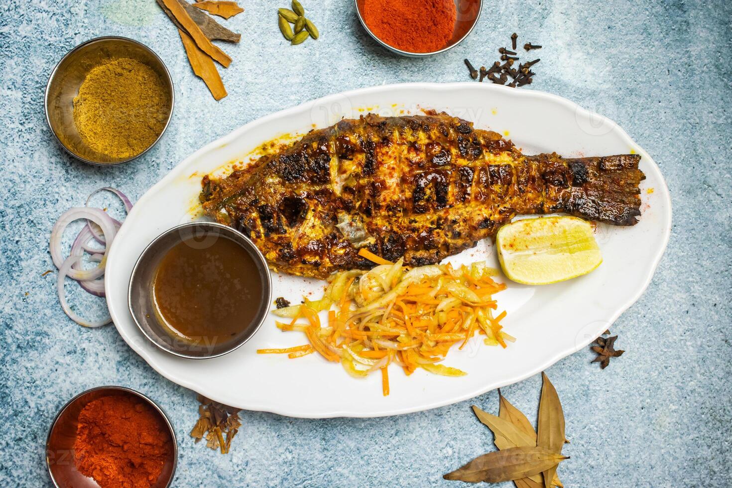 Grilled Coral Fish with salad, lemon and chili sauce served in a dish isolated on grey background top view of bangladesh food photo