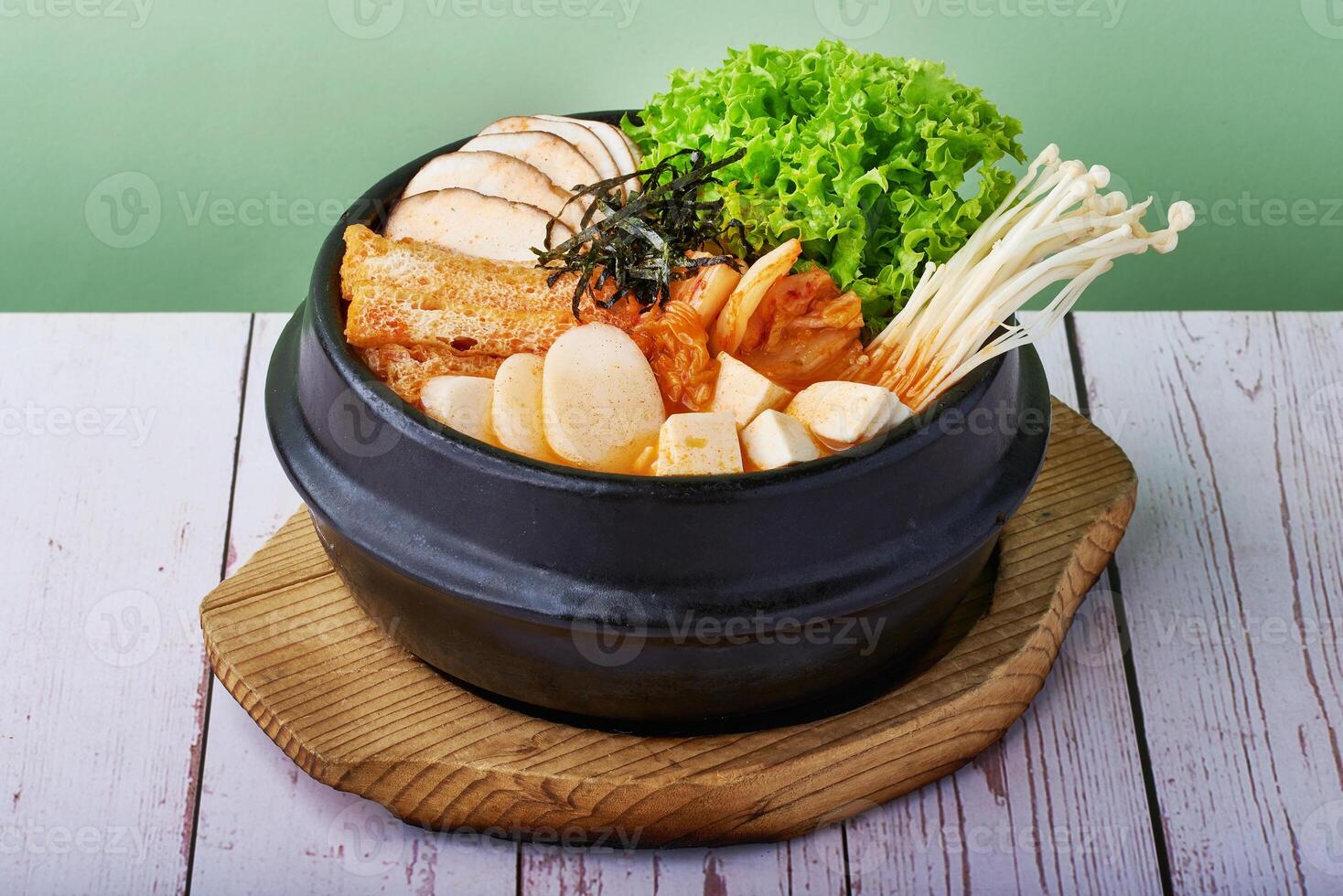 Korean food Ramen Kimchi Jjigae with grilled pork belly and ramen in black metal bowl on wooden background photo