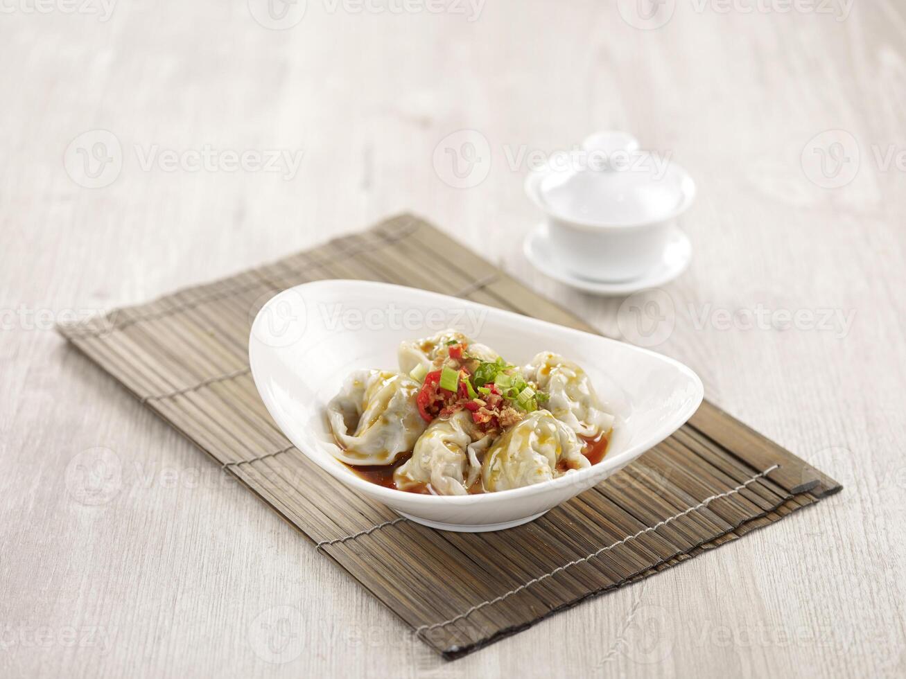 Pork Wanton in Chilli Vinaigrette with chopsticks served in a dish isolated on mat side view on grey background photo
