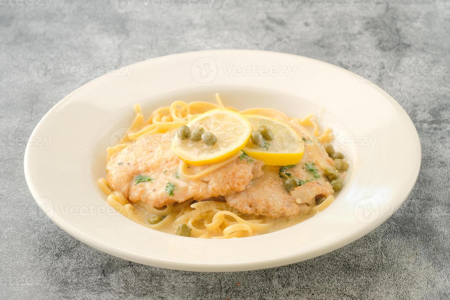 Specialty Chicken Piccata with lemon slice served in a dish isolated on background side view of fastfood photo