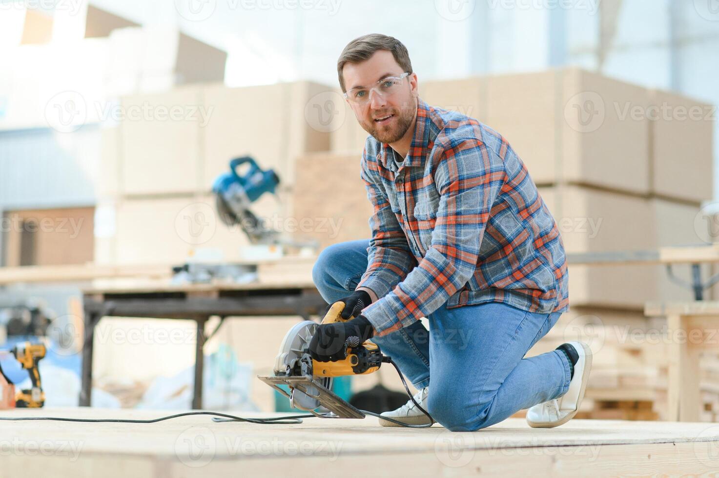 A carpenter works on woodworking the machine tool. Man collects furniture boxes. Saws furniture details with a circular saw. Process of sawing parts in parts. Against the background of the workshop. photo