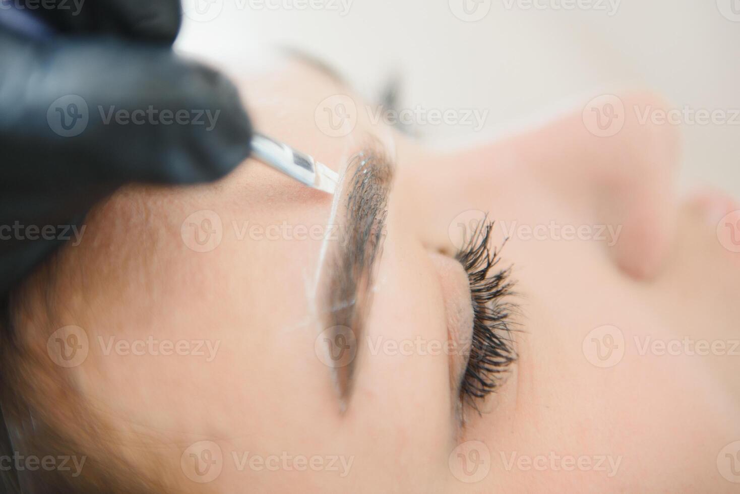 Young woman during professional eyebrow mapping procedure. photo