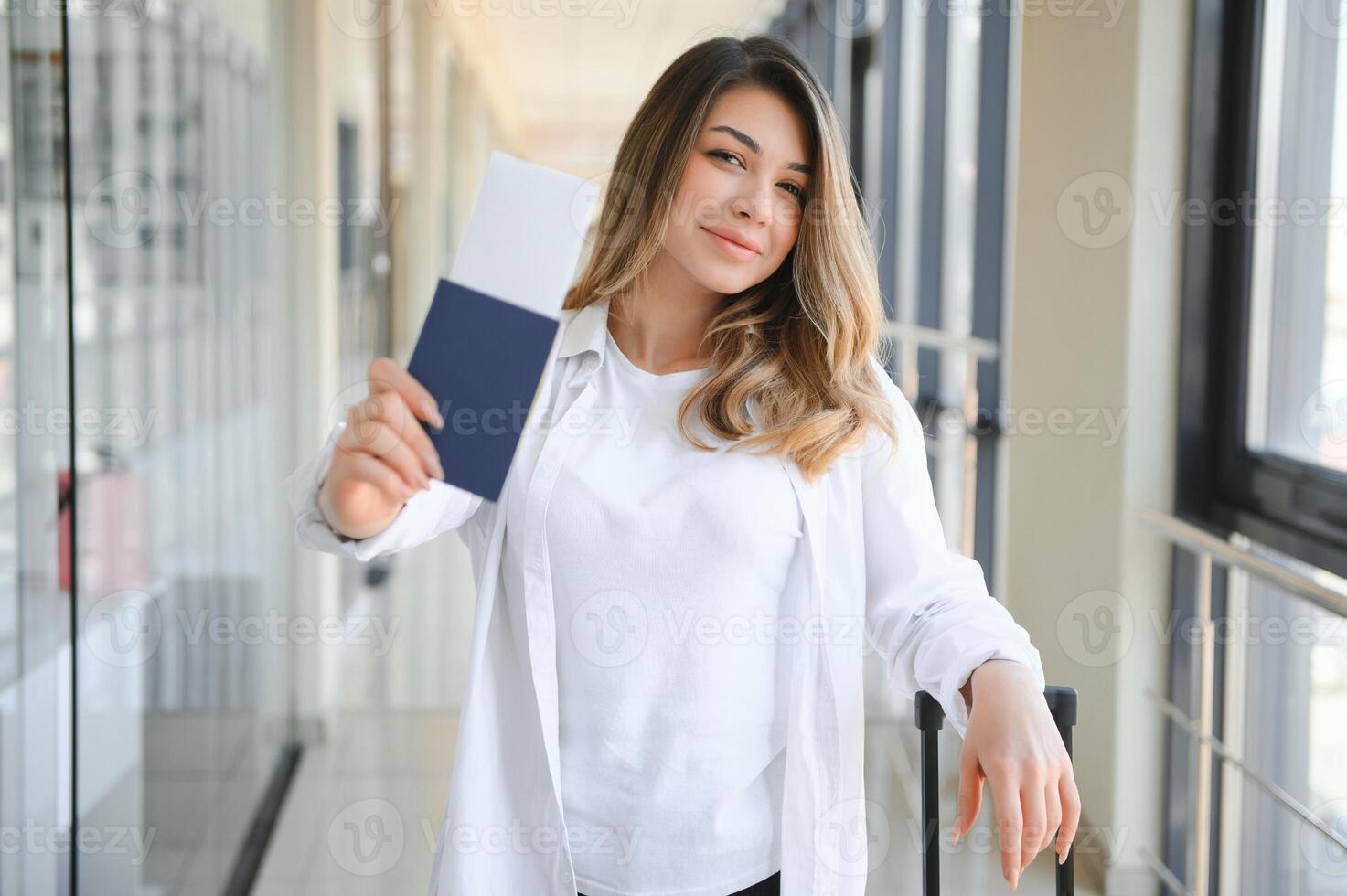 Young pretty stylish woman with luggage at the international airport. Waiting her flight at tax free shopping zone. photo