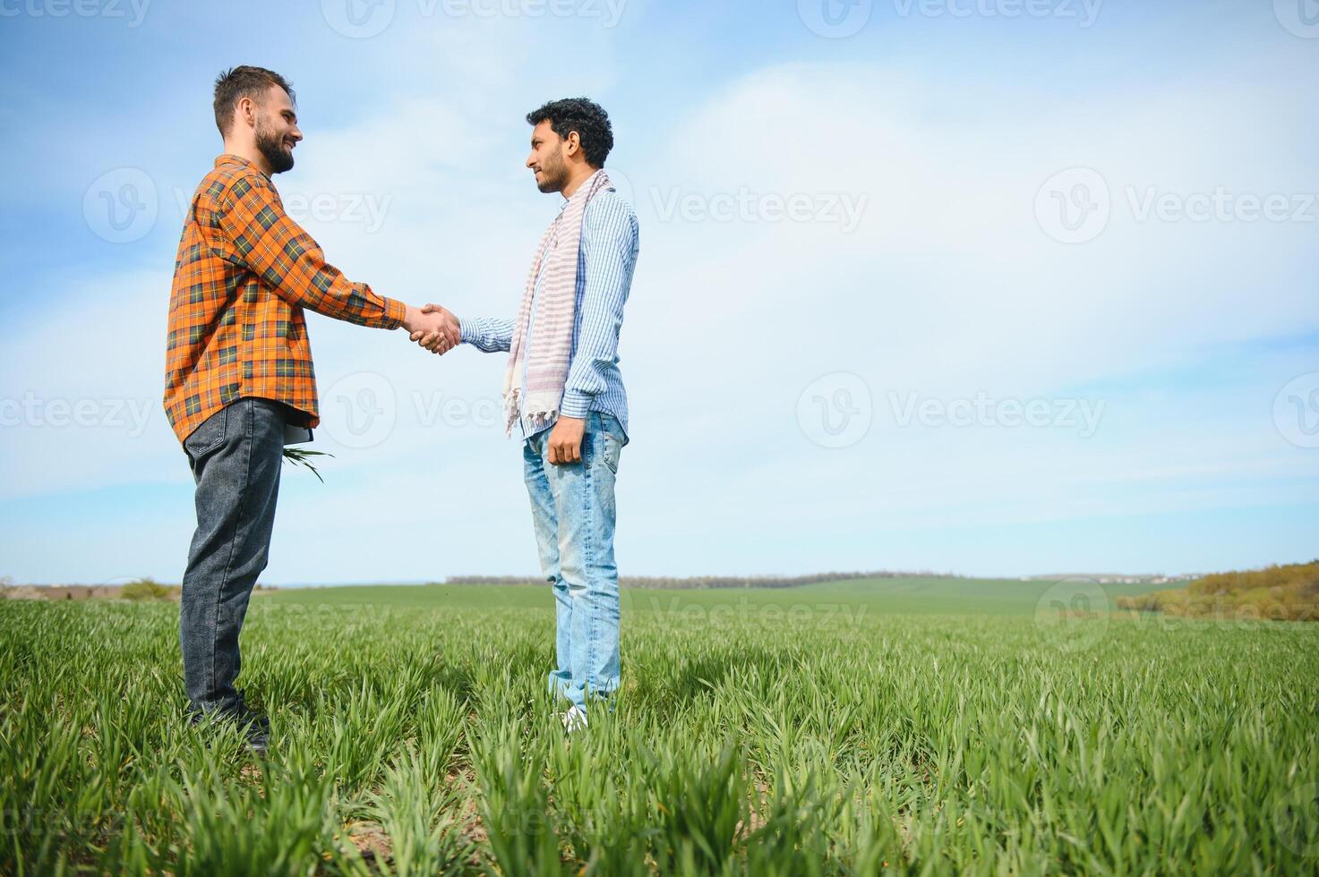 The concept of international relations in agrarian business. Indian and European farmers stand in a field of green wheat photo