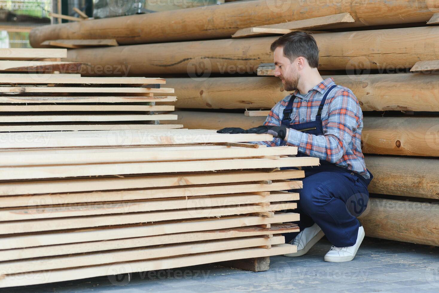 Industrial warehouse of a sawmill, an employee puts his hands on the finished products at the sawmill in the open air. photo