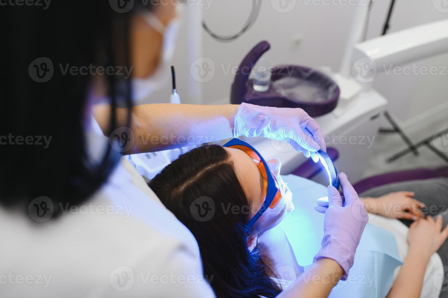 Girl patient in the dental clinic. Teeth whitening UV lamp with photopolymer composition. photo