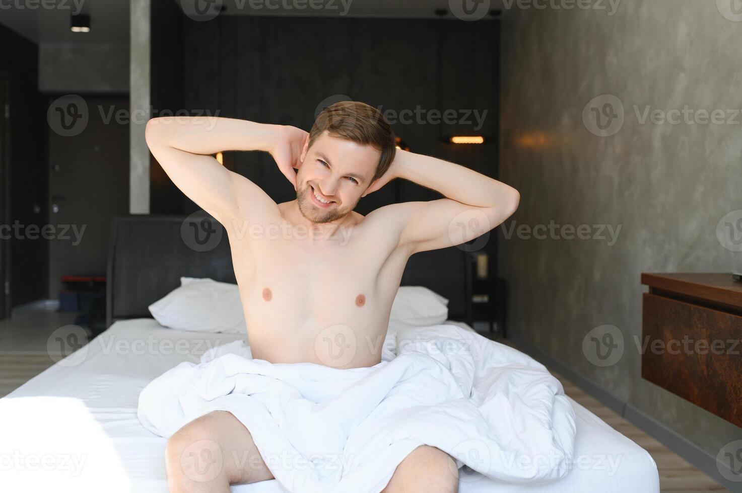 Cheerful Man Waking Up Lying In Cozy Bed At Home On Weekend Morning. Healthy Sleep Concept photo