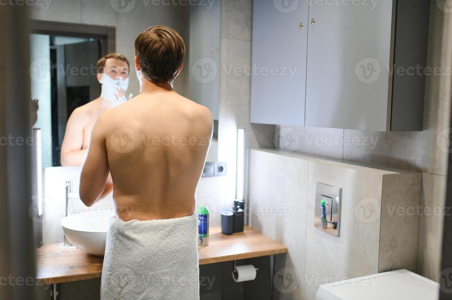 Confident guy using shaver in bathroom photo