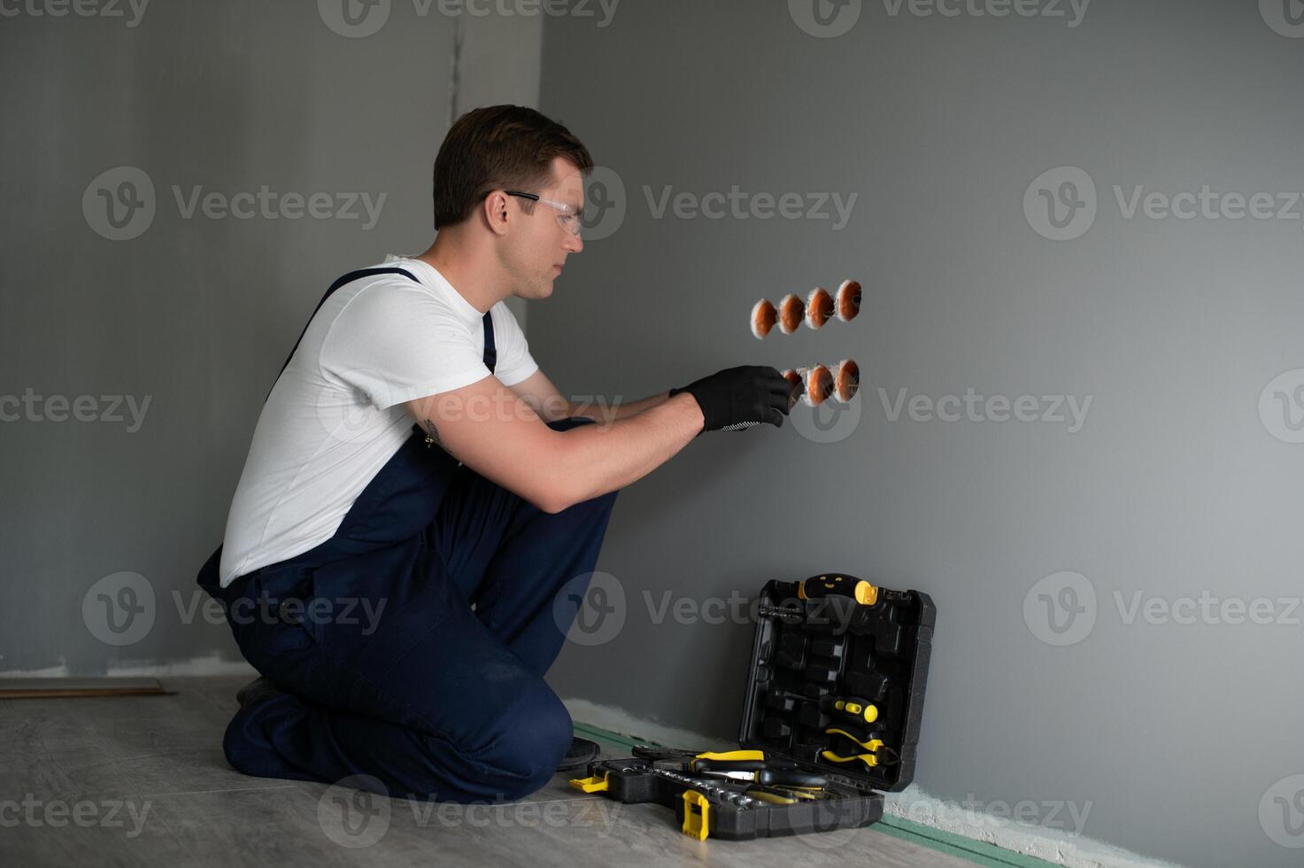 Electrician Builder at work, installation of sockets and switches. Professional in overalls with an electrician's tool. Against the background of the repair site. photo