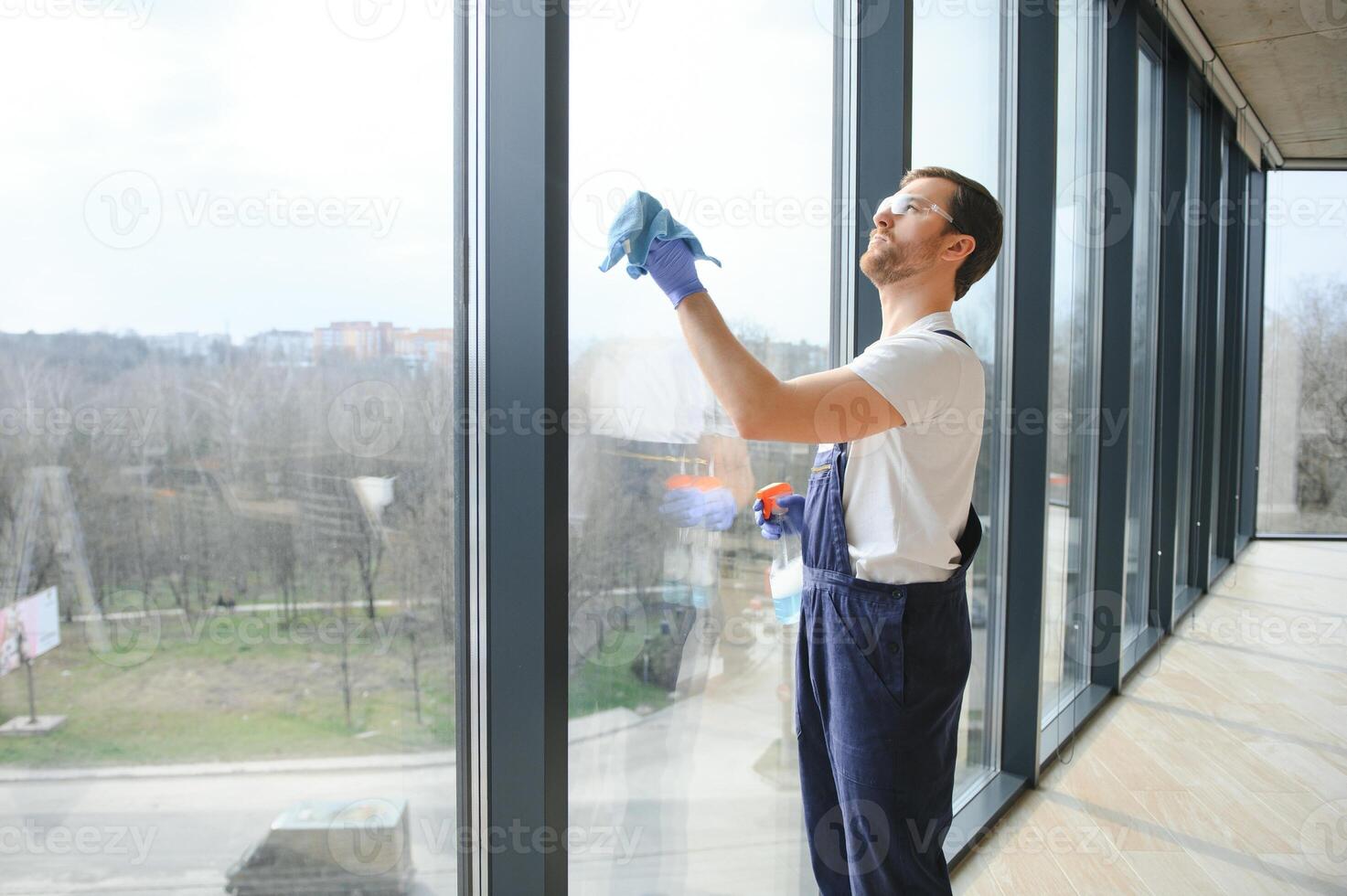 Young man washing window in office photo