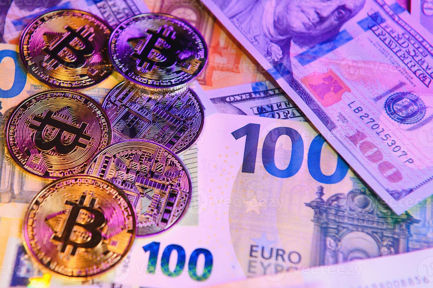 Close up heap of golden bitcoin physical coins on top of Euro, dollar banknotes background, high angle view, selective focus photo