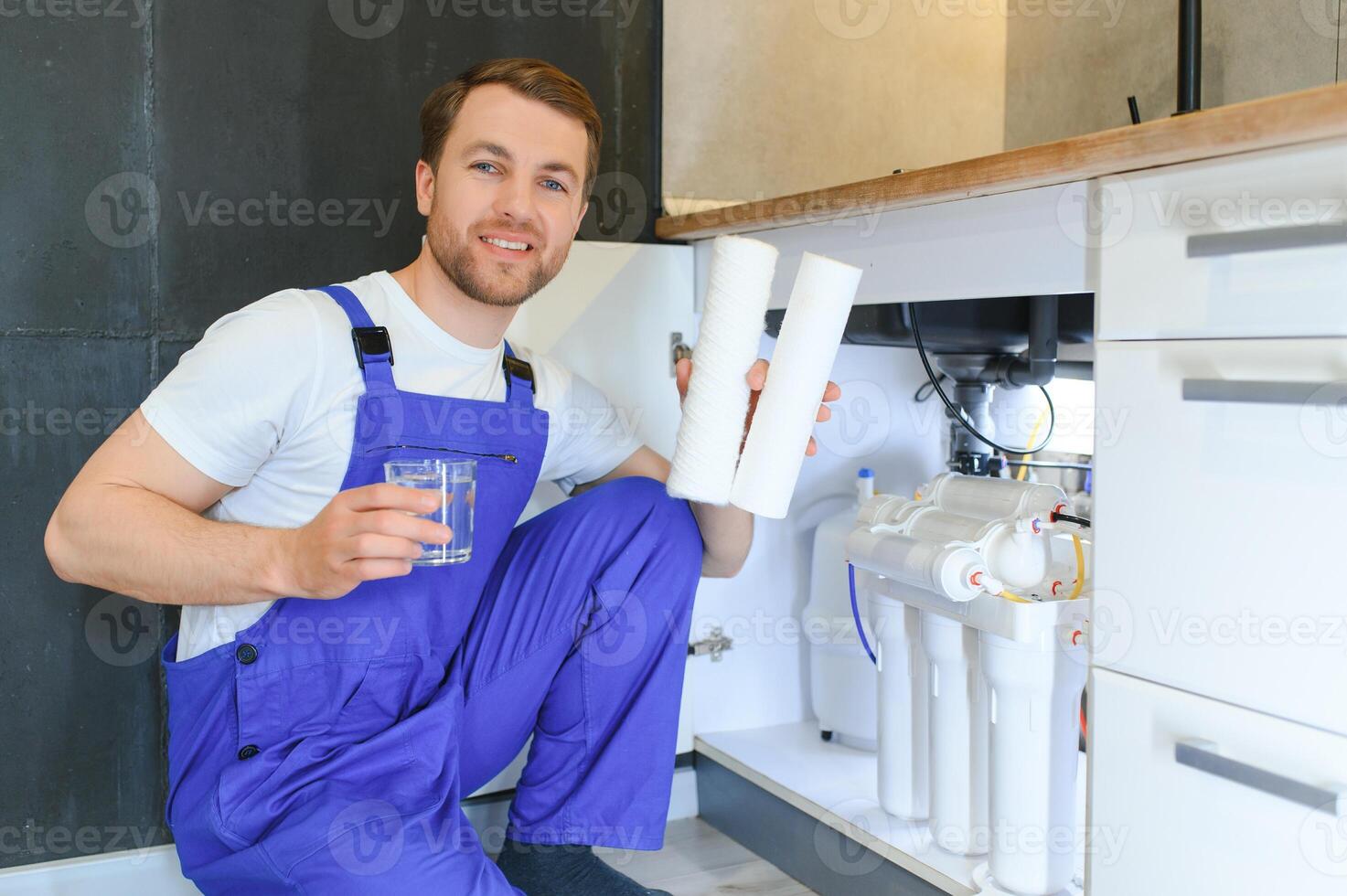 Plumber installs or change water filter. Replacement aqua filter. Repairman installing water filter cartridges in a kitchen. Installation of reverse osmosis water purification system. photo