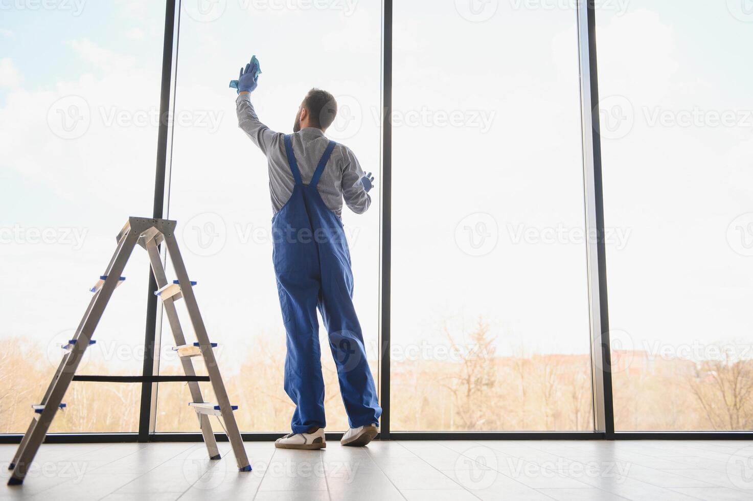 Young man cleaning window in office photo