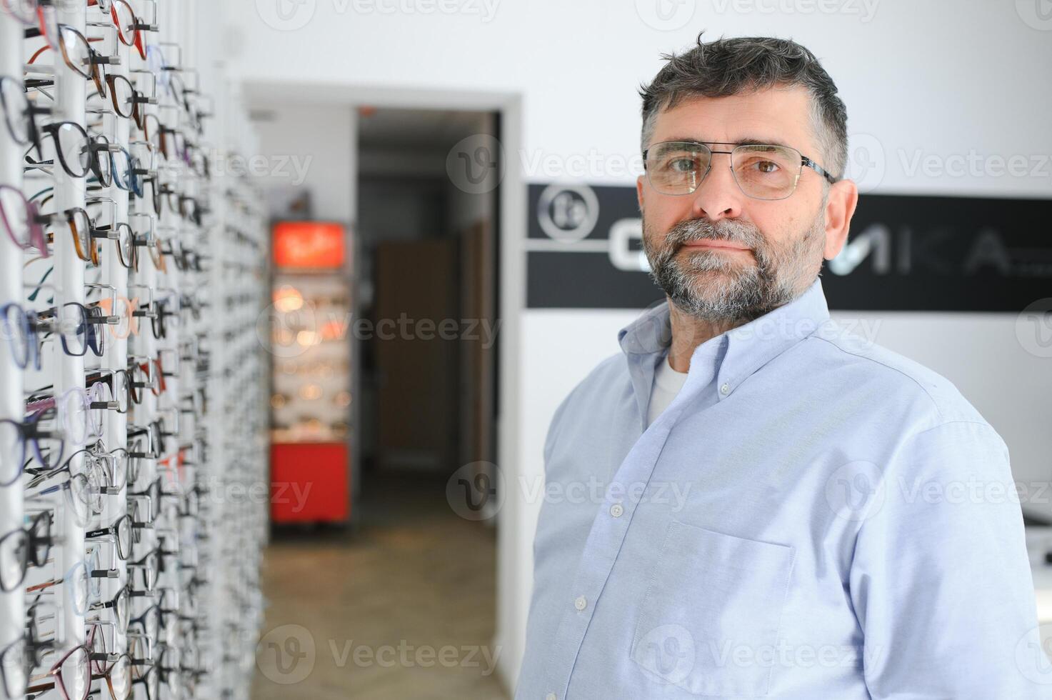 male customer choosing glasses in optics store photo