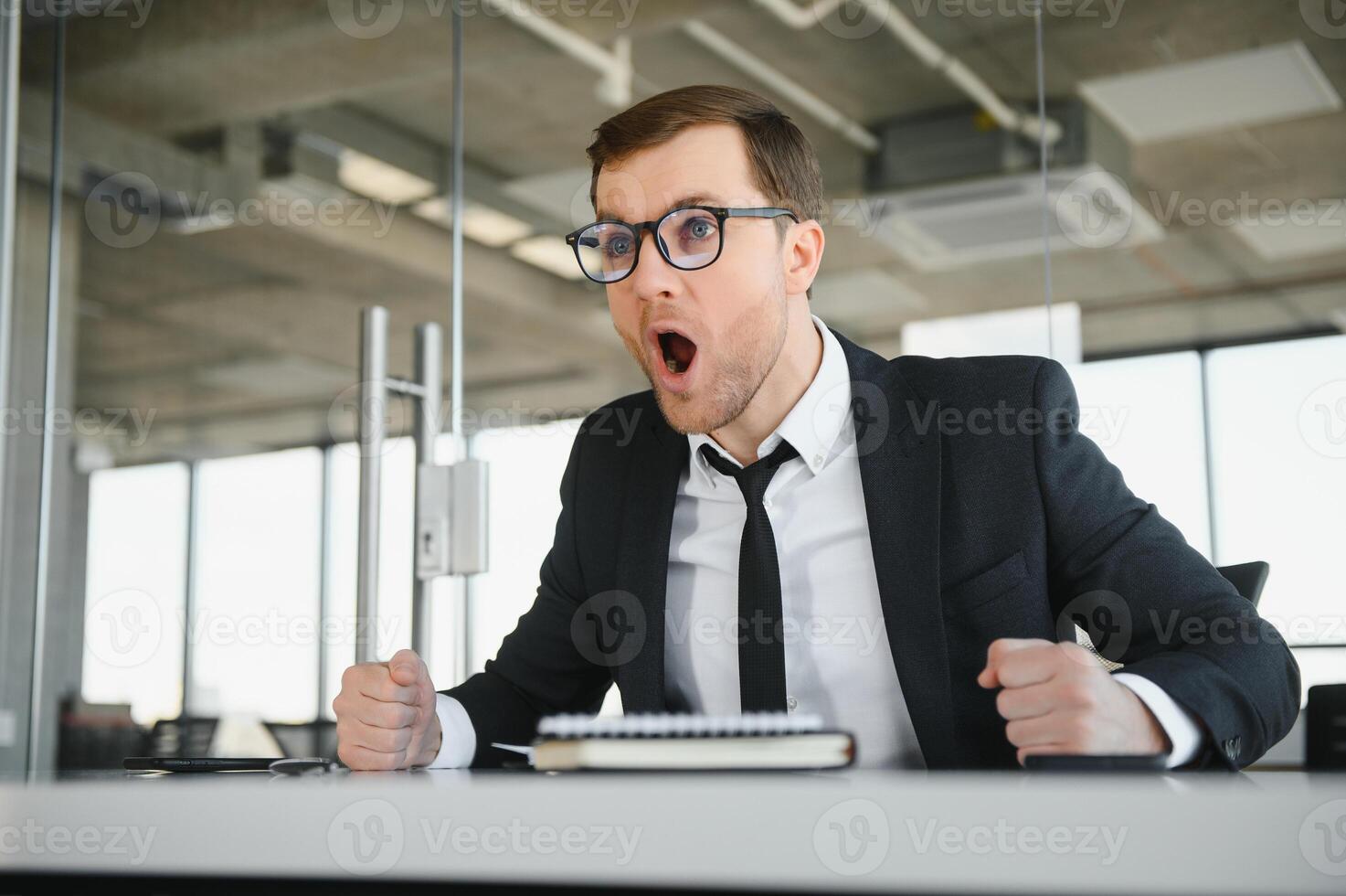 Angry businessman sitting at his desk and screaming at his employees. photo