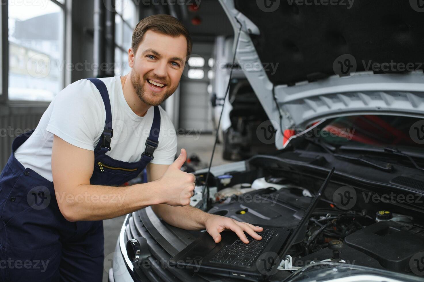 With laptop. Adult man in uniform works in the automobile salon. photo