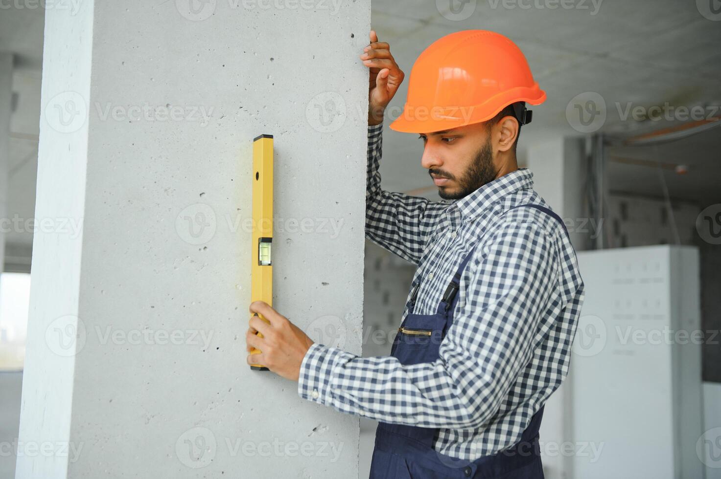 Indian construction site manager standing wearing helmet, thinking at construction site. Portrait of mixed race manual worker or architect. photo