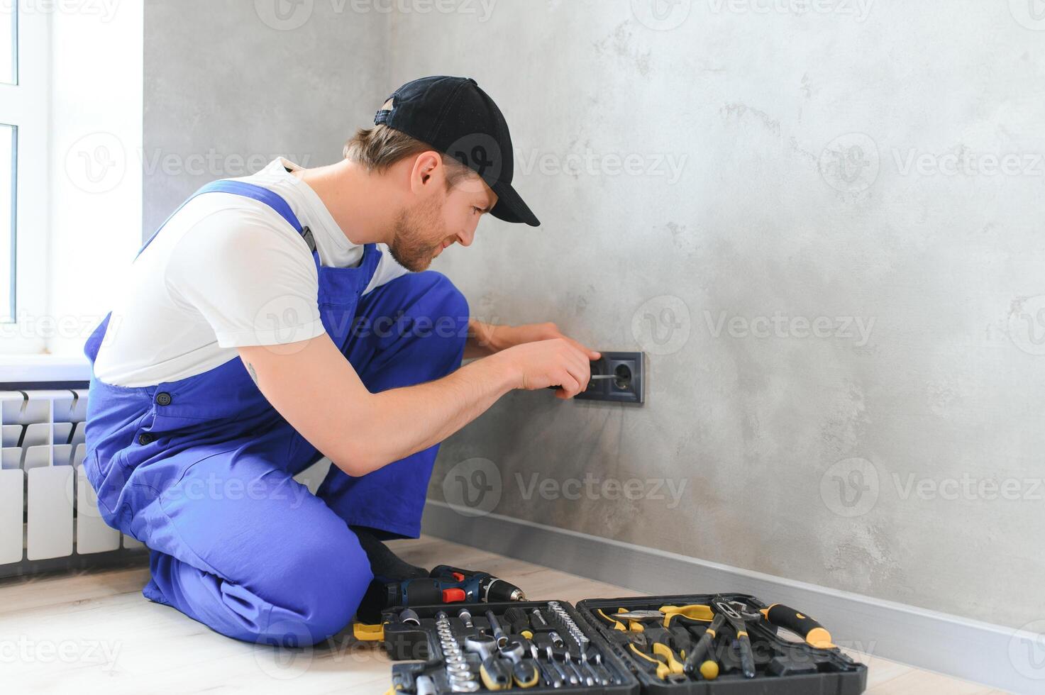 Construction worker electrician assembles an electrical outlet in an apartment photo
