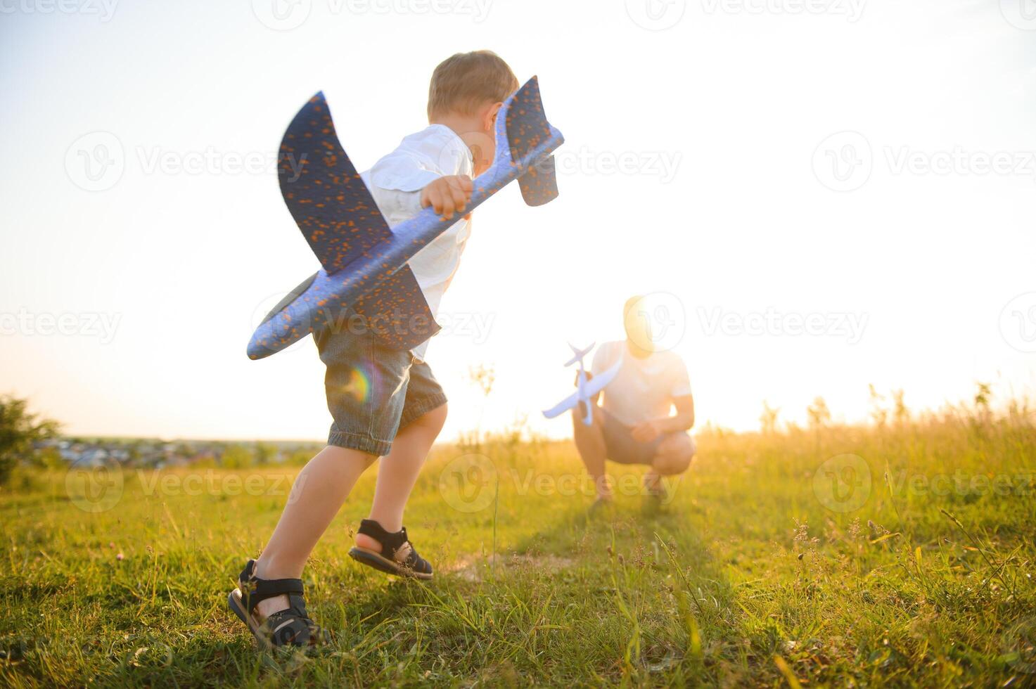 Dad with his son at sunset in nature. A father plays with toy airplanes with his son at sunset. father's day photo