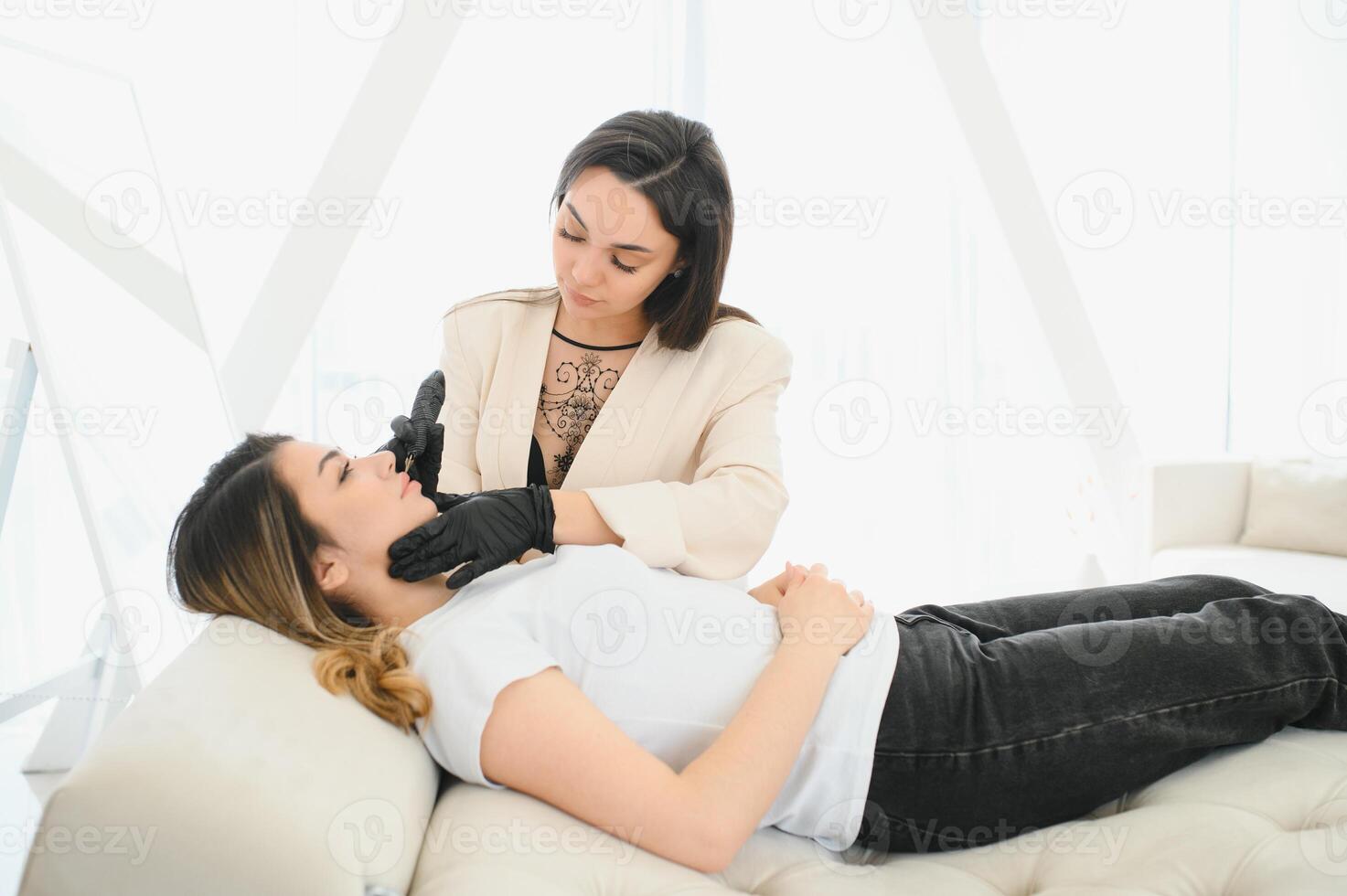 Young woman getting permanent makeup on lips in beautician salon photo