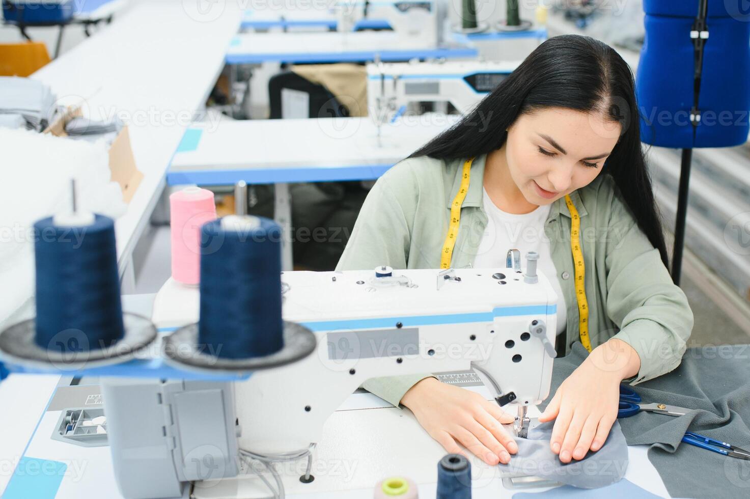 Young woman working as seamstress in clothing factory. photo