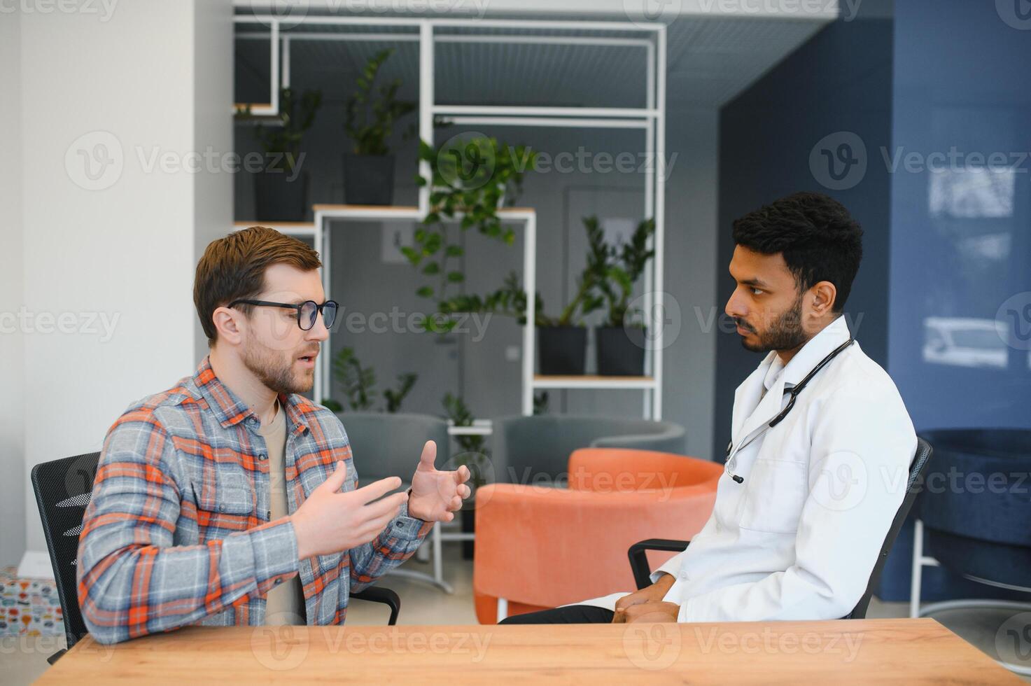 Indian doctor in white gown seeing patients in office. photo