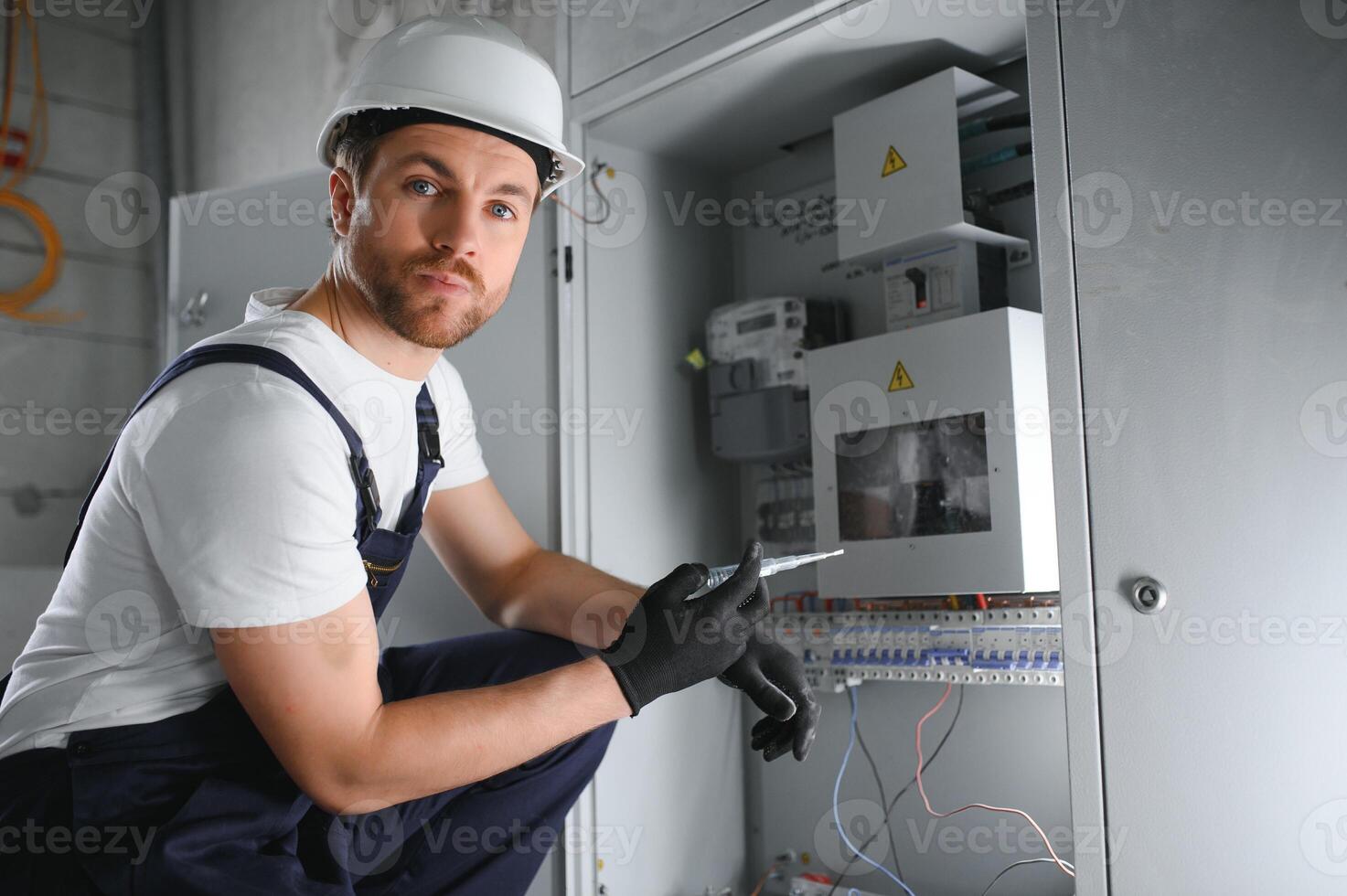 Man, an electrical technician working in a switchboard with fuses. Installation and connection of electrical equipment. Professional with tools in hand. concept of complex work, space for text. photo