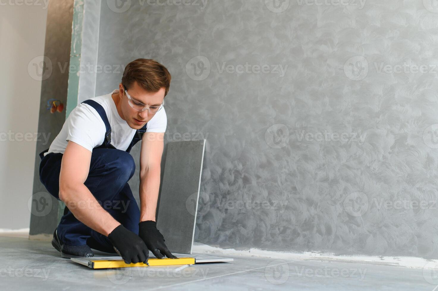 Worker installing ceramic tile on floor near wall. photo