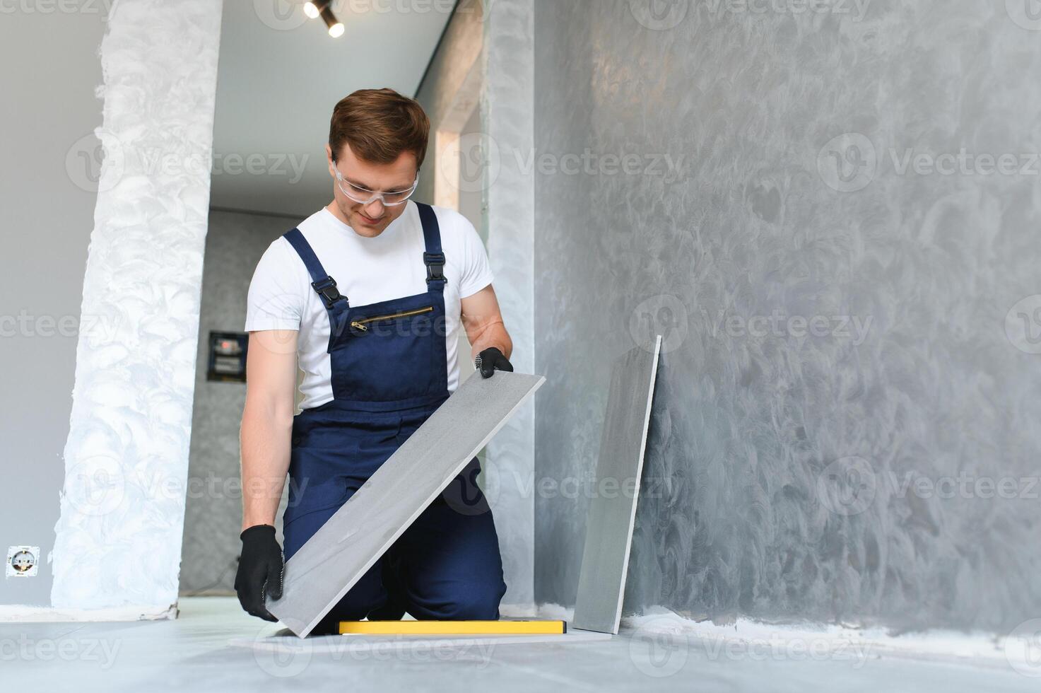 industrial worker, handyman installing big ceramic tiles photo