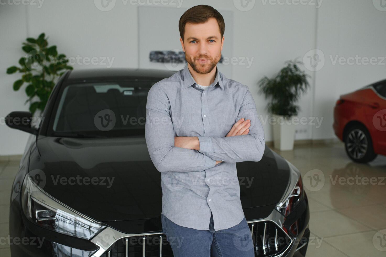 Final decision. Shot of a handsome young man standing in front of a new car at the dealership thinking rubbing his chin photo