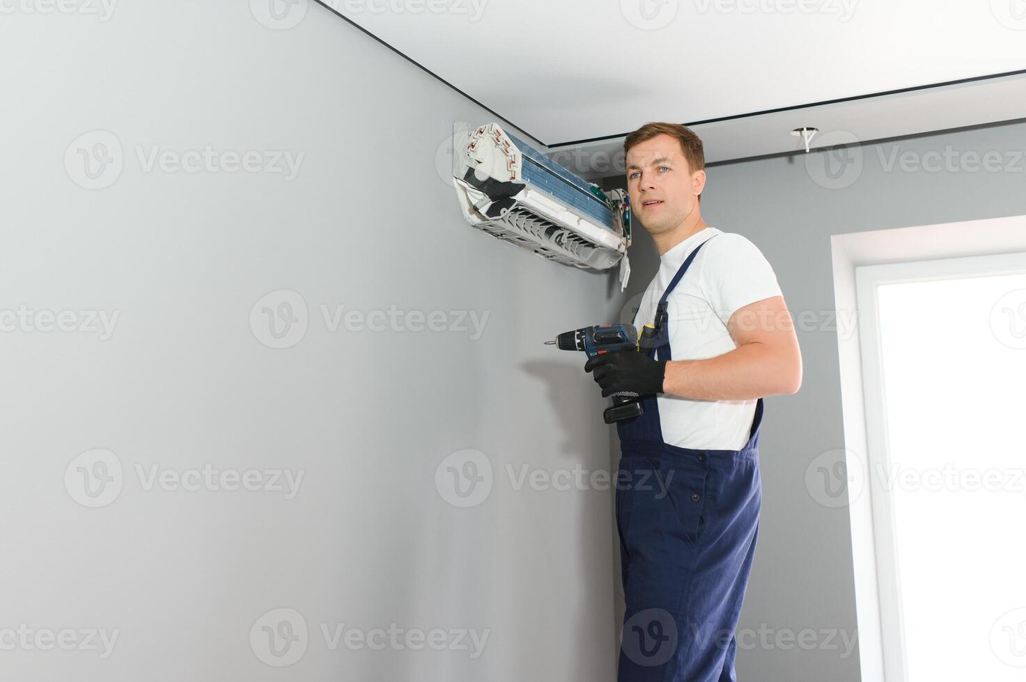handsome young man electrician installing air conditioning in a client house photo