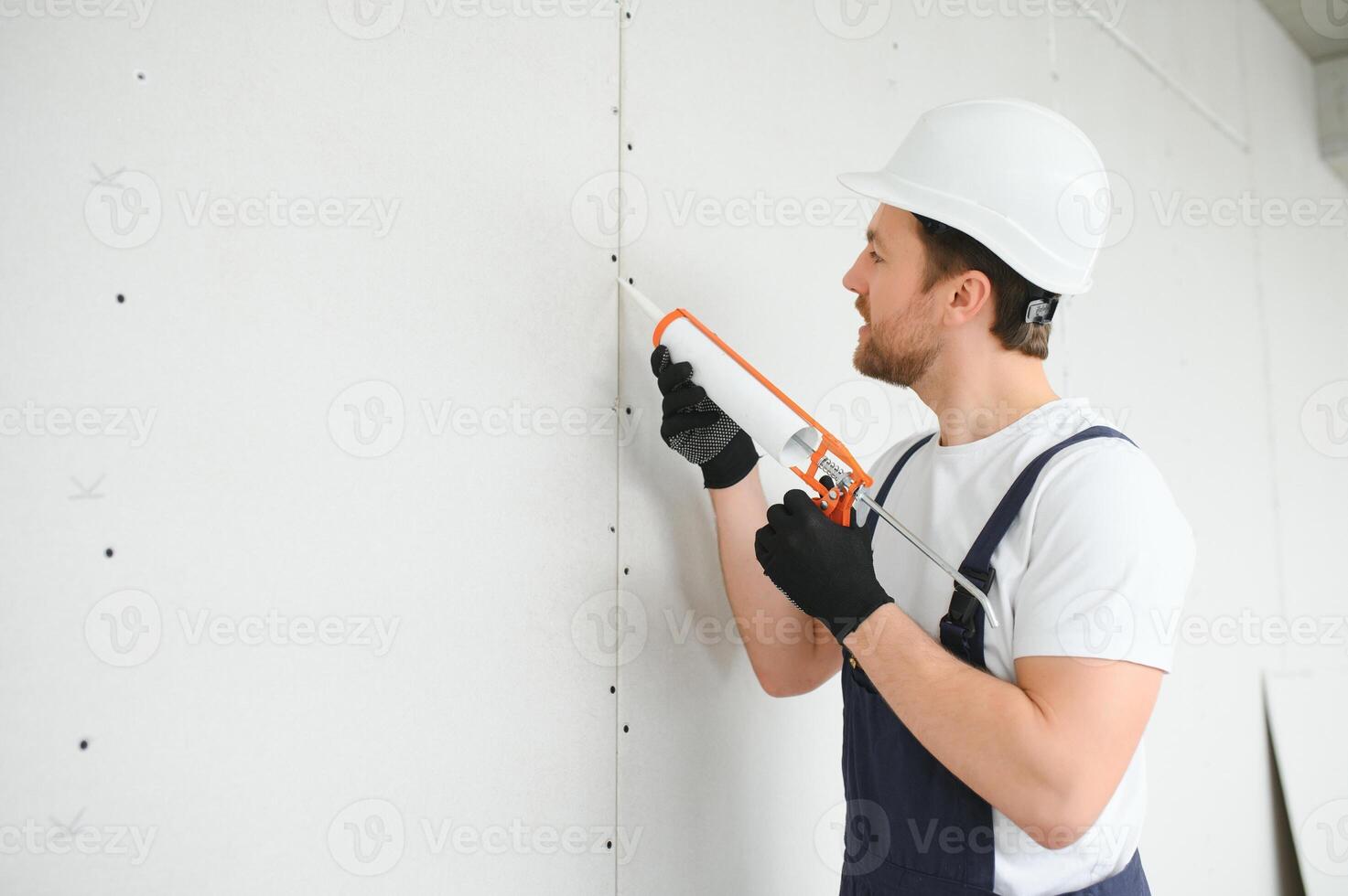 Professional Workman Applying Silicone Sealant With Caulking Gun on the Wall photo