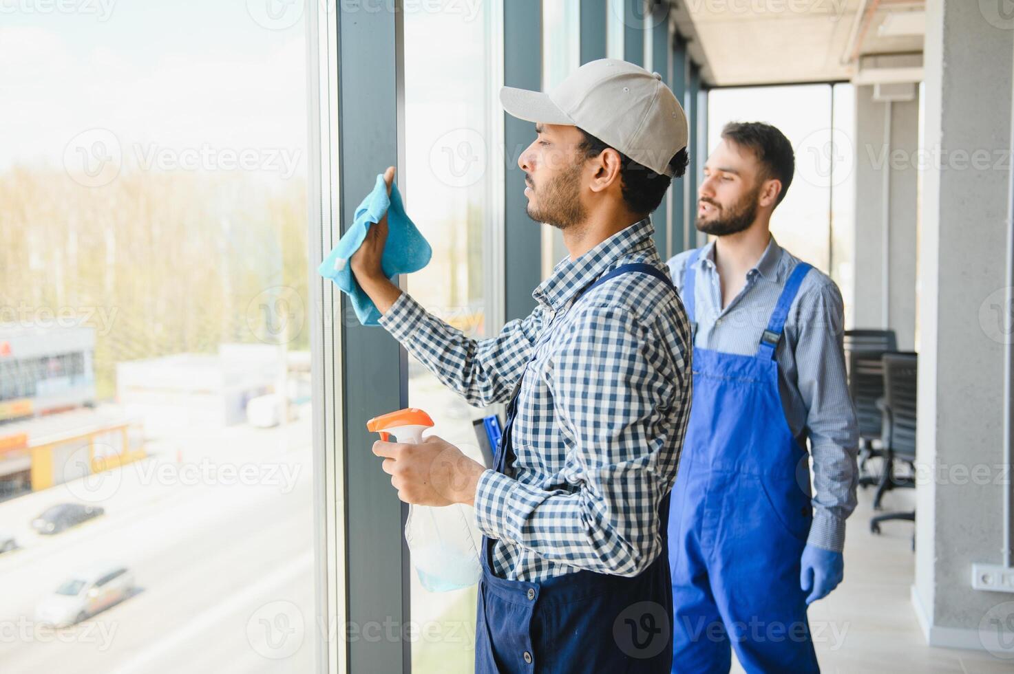 multiethnic professional cleaners in uniform washing large windows in office photo