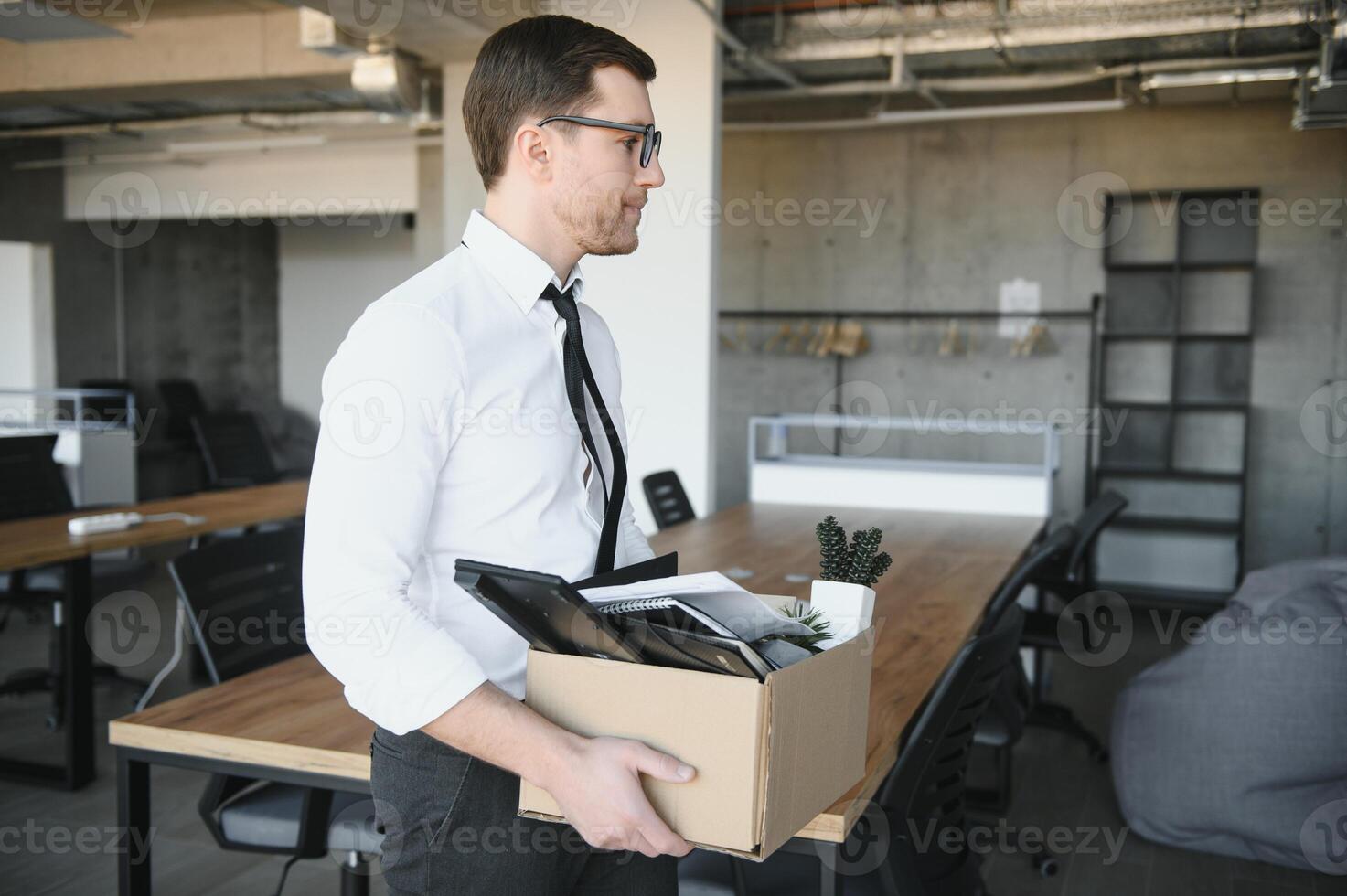 Sad Fired. Let Go Office Worker Packs His Belongings into Cardboard Box and Leaves Office. Workforce Reduction, Downsizing, Reorganization, Restructuring, Outsourcing. Mass Unemployment Market Crisis photo